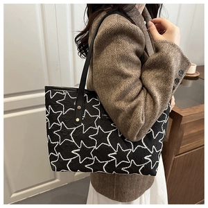 Close-up of black tote bag featuring white star embroidery and gold rivet details
