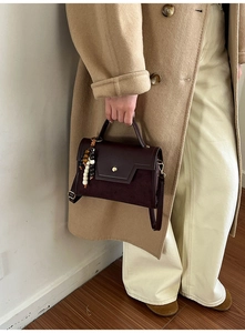 Close-up of retro dark brown leather bag with textured suede and vintage bead charm details