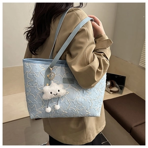 Detail of light blue tote bag with star stitching and plush cloud charm accessory