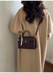 Détail du sac bandoulière rétro marron foncé avec texture en daim et breloque en bois