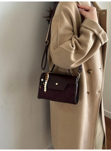 Detail of dark brown vintage baguette bag with suede patchwork and beaded tassel charm