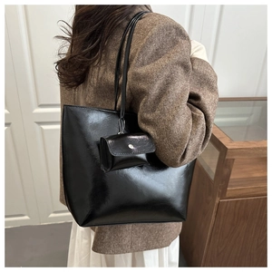 Detail view of large black PU leather tote bag with matching mini coin purse on shoulder