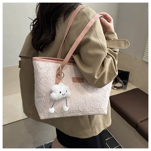 Detail of star pattern tote bag with plush cloud charm and pink leather strap