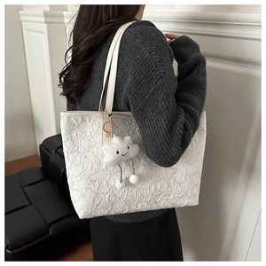 Detail of white tote bag with cloud charm and textured fabric on female model