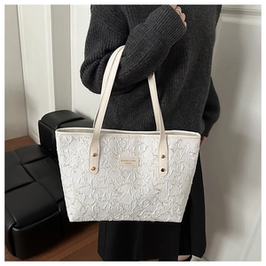 Detail of the textured pleated cream tote bag with elegant metallic logo and double straps