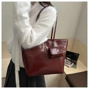 Detail of dark red patent leather tote bag with glossy finish and matching mini pouch charm