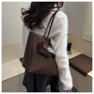 Detail view of large dark brown leather tote bag with matching mini pouch and long straps