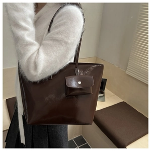 Detail of a dark brown glossy tote bag with matching detachable hanging chain purse