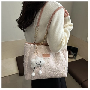 Detailed shot of a cream quilted tote bag with chain strap and fluffy cloud charm accessory