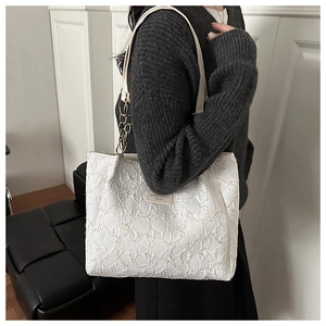 Detail of white textured tote bag with pleated fabric and gold metal chain strap