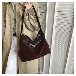 Close-up of a large brown suede tote bag featuring metallic buckles and leather straps