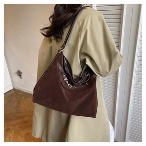 Close-up of vintage brown suede tote bag featuring a retro metal buckle and leather strap