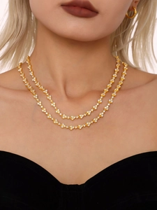Detailed view of luxury layered 18k gold plated necklace with zircon pavé flower motifs