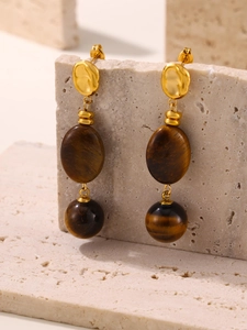 Détail de boucles d'oreilles œil de tigre avec clous dorés martelés et pierres naturelles
