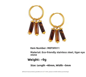 Détail de créoles en acier doré 18 carats avec pendentifs en pierre œil de tigre