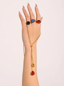 Detail of 18K gold plated jewelry set with resin cabochon rings and tassel link bracelet