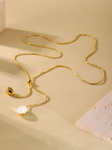Close-up of golden snake chain with adjustable drop and white resin stone pendant