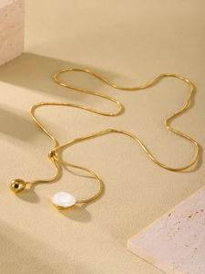 Detail of 18K gold snake chain necklace with white resin pendant on stone background
