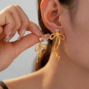 Detailed close-up of bow ribbon tassel earrings with 18k gold plating and heart zircon