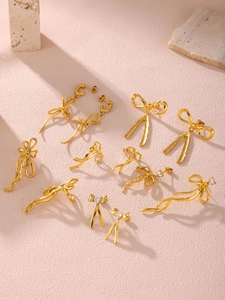 Macro shot of 18K gold-plated bow jewelry set with tassels and crystals on stone background