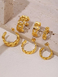 Detail of 6-piece gold chain link C-shaped earrings set on minimalist stone surface