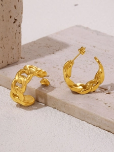 Macro shot of 18K gold plated Cuban link C-shaped hoop earrings on beige stone