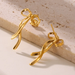 Elegant 18K gold plated bow ribbon tassel earrings on a textured stone display