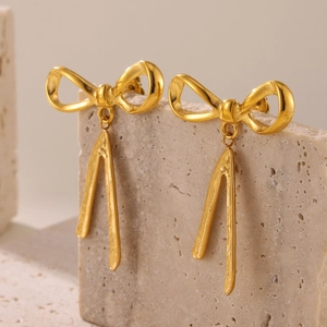 Elegant 18K gold-plated bowknot tassel earrings displayed on a natural stone base