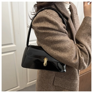 Détail d'un sac à bandoulière en cuir verni noir brillant avec fermoir doré