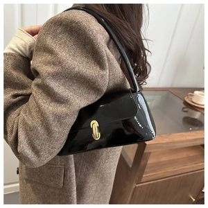 Detail of black patent leather baguette bag with gold buckle on wool blazer