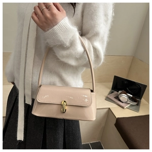Détail du sac baguette beige élégant avec finition brillante et fermoir tournant doré