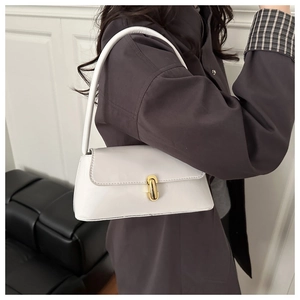 Détail du sac baguette blanc avec fermoir capsule doré sur cuir verni brillant
