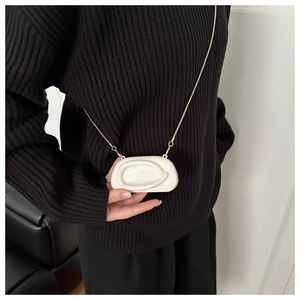 Detail of marble pattern acrylic mini crossbody bag with gold chain on black knitwear