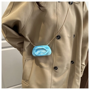 Blue marble texture acrylic shell bag with elegant gold chain worn as a crossbody accessory