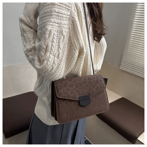Sac bandoulière chic à motif léopard avec chaîne porté par un mannequin en intérieur