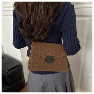 Sac bandoulière léopard avec chaîne en métal porté sur une tenue décontractée chic