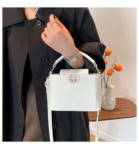 Detail of white leather mini bag featuring gold circular hardware and elegant texture