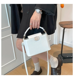 Detailed view of white crossbody bag with gold metal clasp and textured leather