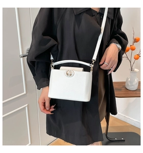Detailed close-up of a white lychee grain handbag with golden logo and slender shoulder strap