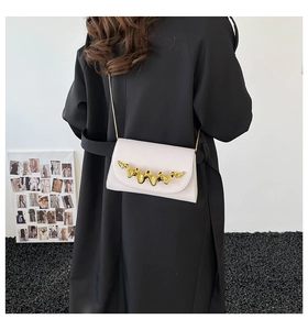 Sac bandoulière chic en cuir beige avec boucle dorée vague porté par un mannequin