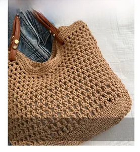 Close-up of brown woven tote bag featuring hollow crochet pattern and leather handles