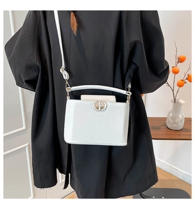Close-up of a white textured leather crossbody bag with circular metal buckle detail