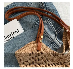Close-up of woven straw texture with brown leather strap and gold rivet details