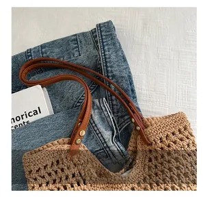 Close-up of woven cotton tote bag featuring brown leather handles and gold metal rivets