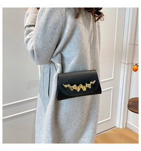 Détail du sac bandoulière noir avec décor en métal doré et bandoulière en chaîne