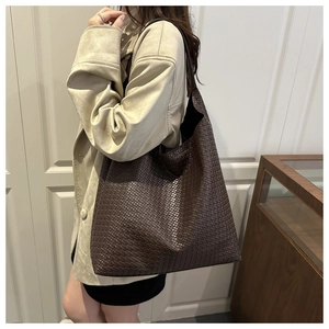 Side view of large dark brown woven tote bag carried on a shoulder for daily commute