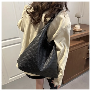 Close-up of large black woven tote bag showing detailed texture and hobo shape