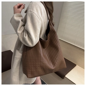 Detailed close-up of dark brown woven tote bag featuring high-quality leather texture