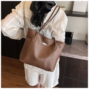 Détail du sac cabas en cuir grainé marron foncé avec logo en métal et longues bandoulières