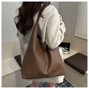 Detail view of the intricate hand-woven dark brown leather texture on a hobo tote bag